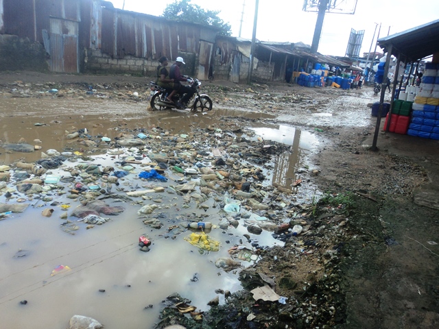 Flooded urban unpaved street with plastic waste littered everywhere. Image used to denote the plastic waste problem in Nigerian urban areas